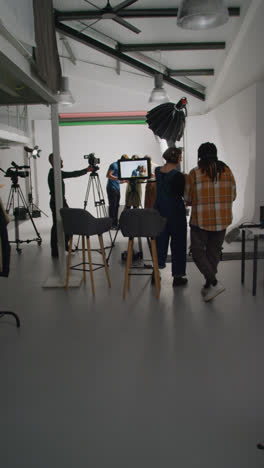 Vídeo-Vertical-De-Actores-Trabajando-En-El-Set-De-Rodaje-De-Una-Película-O-Un-Vídeo-En-El-Estudio-Con-El-Director,-El-Camarógrafo,-El-Técnico-De-Sonido-Y-El-Asistente.